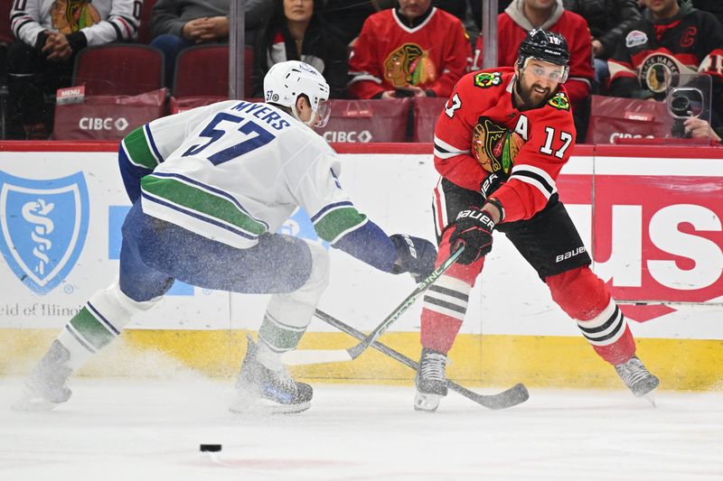 Feb 13, 2024; Chicago, Illinois, USA; Chicago Blackhawks forward Nick Foligno (17) passes the puck past Vancouver Canucks defenseman Tyler Myers (57) in the first period at United Center. Mandatory Credit: Jamie Sabau-USA TODAY Sports