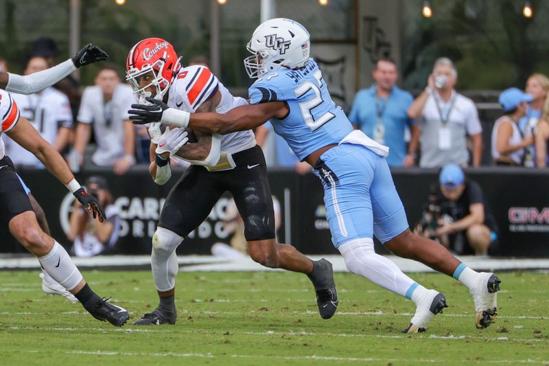 Nov 11, 2023; Orlando, Florida, USA; UCF Knights linebacker Walter Yates III (27) tackles against Oklahoma State Cowboys running back Ollie Gordon II (0) during the first quarter at FBC Mortgage Stadium. Mandatory Credit: Mike Watters-USA TODAY Sports