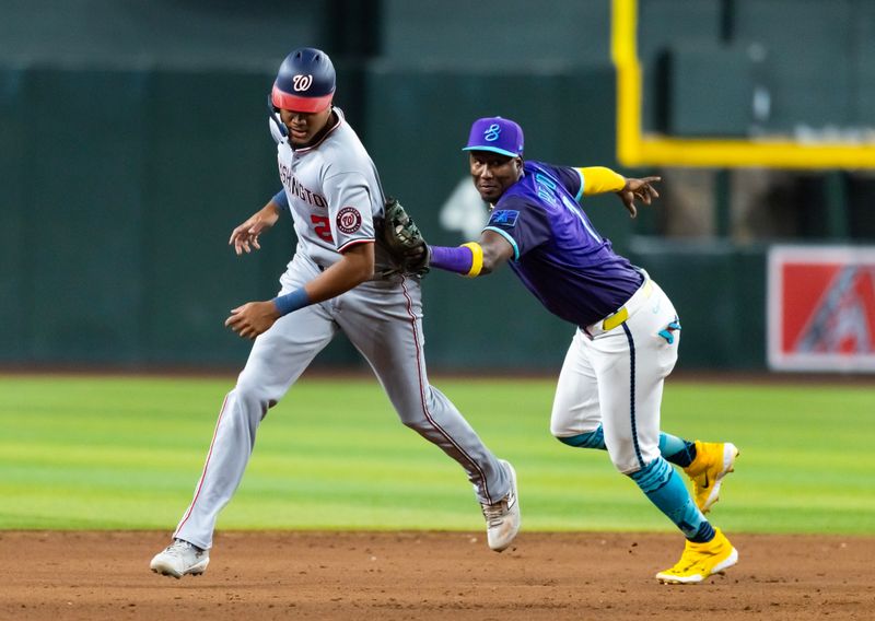 May 30, 2025; Phoenix, Arizona, USA; Washington Nationals base runner James Wood (left) is tagged out by Arizona Diamondbacks shortstop Geraldo Perdomo during a sixth inning rundown at Chase Field. Mandatory Credit: Mark J. Rebilas-Imagn Images
