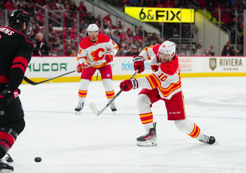 Mar 10, 2024; Raleigh, North Carolina, USA;  Calgary Flames center Jonathan Huberdeau (10) takes a shot against the Carolina Hurricanes during the second period at PNC Arena. Mandatory Credit: James Guillory-USA TODAY Sports