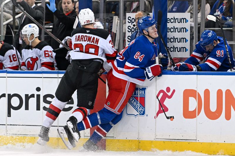 Dec 2, 2024; New York, New York, USA;  New Jersey Devils left wing Mike Hardman (39) checks New York Rangers center Adam Edstrom (84) into the boards at during the first period Madison Square Garden. Mandatory Credit: Dennis Schneidler-Imagn Images