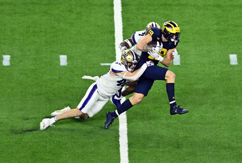 Jan 8, 2024; Houston, TX, USA; Michigan Wolverines tight end Colston Loveland (18) is tackled by Washington Huskies linebacker Carson Bruener (42) and cornerback Dominique Hampton (7) during the second quarter in the 2024 College Football Playoff national championship game at NRG Stadium. Mandatory Credit: Maria Lysaker-USA TODAY Sports