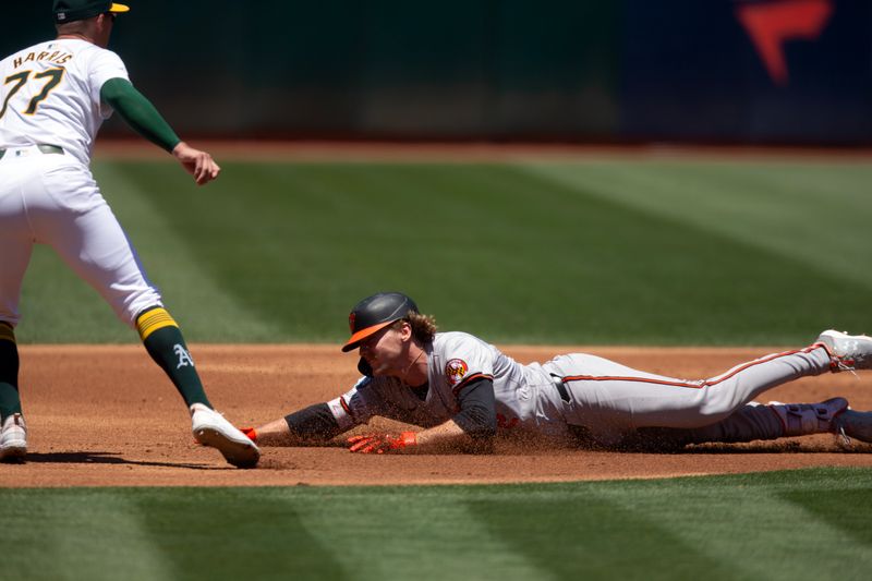 Jul 7, 2024; Oakland, California, USA; Baltimore Orioles shortstop Gunnar Henderson (2) slides into third base with a triple as Oakland Athletics third baseman Brett Harris (77) waits on the relay during the second inning at Oakland-Alameda County Coliseum. Mandatory Credit: D. Ross Cameron-USA TODAY Sports