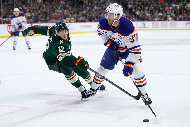 Dec 20, 2025; Saint Paul, Minnesota, USA; Edmonton Oilers center Connor McDavid (97) skates with the puck as Minnesota Wild left wing Matt Boldy (12) defends during the third period at Grand Casino Arena. Mandatory Credit: Matt Krohn-Imagn Images