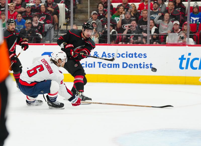 May 10, 2025; Raleigh, North Carolina, USA; Carolina Hurricanes defenseman Dmitry Orlov (7) gets the shot past Washington Capitals defenseman Jakob Chychrun (6) during the first period in game three of the second round of the 2025 Stanley Cup Playoffs at Lenovo Center. Mandatory Credit: James Guillory-Imagn Images