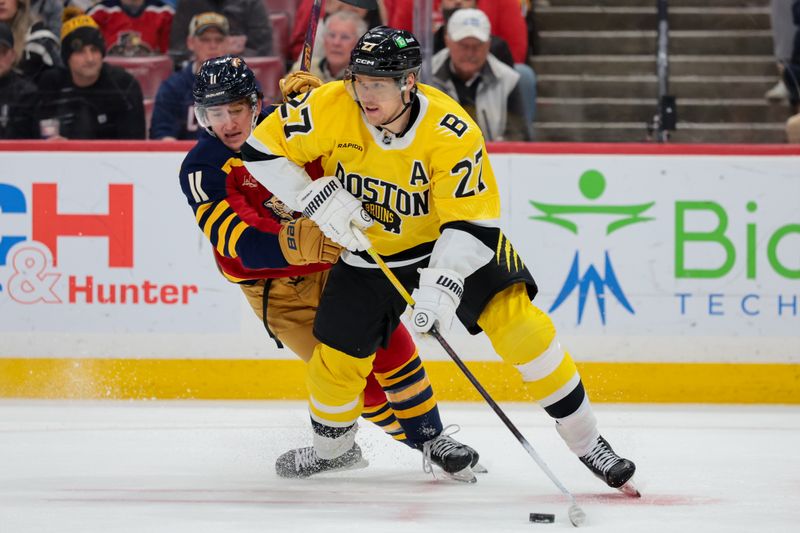 Feb 4, 2026; Sunrise, Florida, USA; Boston Bruins defenseman Hampus Lindholm (27) moves the puck against Florida Panthers right wing MacKie Samoskevich (11) during the first period at Amerant Bank Arena. Mandatory Credit: Sam Navarro-Imagn Images