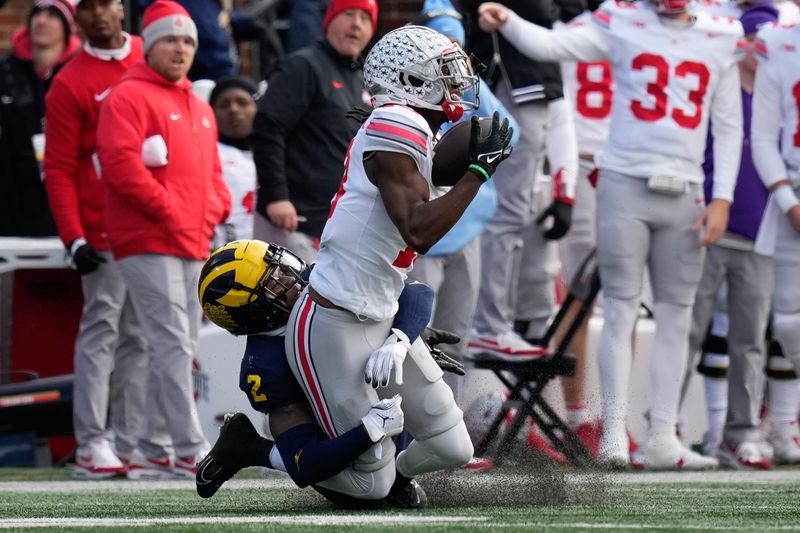 Nov 25, 2023; Ann Arbor, Michigan, USA; Ohio State Buckeyes wide receiver Marvin Harrison Jr. (18) catches a pass while being defended by Michigan Wolverines defensive back Will Johnson (2) during the first half of the NCAA football game at Michigan Stadium. Mandatory Credit: Adam Cairns-USA TODAY Sports