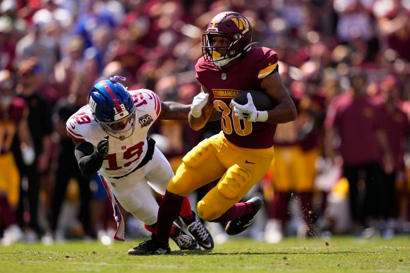 Washington Commanders running back Austin Ekeler (30) runs against New York Giants linebacker Isaiah Simmons (19) during the first half of an NFL football game in Landover, Md., Sunday, Sept. 15, 2024. (AP Photo/Matt Slocum)