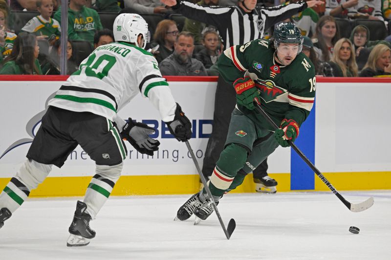 Sep 29, 2024; Saint Paul, Minnesota, USA;  Minnesota Wild forward Devin Shore (19) controls the puck as Dallas Stars defenseman Kyle Capobianco (20) defends during the second period at Xcel Energy Center. Mandatory Credit: Nick Wosika-Imagn Images