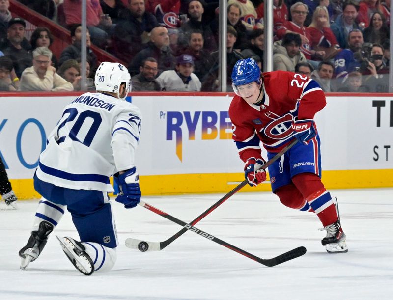 Mar 9, 2024; Montreal, Quebec, CAN; Montreal Canadiens forward Cole Caufield (22) plays the puck and Toronto Maple Leafs defenseman Joel Edmundson (20) defends during the second period at the Bell Centre. Mandatory Credit: Eric Bolte-USA TODAY Sports