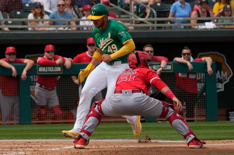 Mar 23, 2024; Mesa, Arizona, USA; Oakland Athletics first baseman Ryan Noda (49) scores a run while avoiding Los Angeles Angels catcher Matt Thaiss (21) in the second inning at Hohokam Stadium. Mandatory Credit: Rick Scuteri-USA TODAY Sports