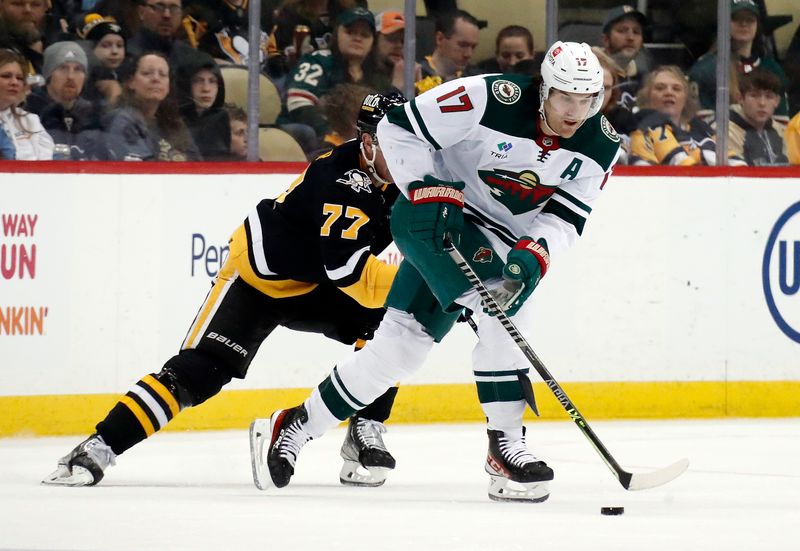 Apr 6, 2023; Pittsburgh, Pennsylvania, USA; Minnesota Wild left wing Marcus Foligno (17) moves the puck against Pittsburgh Penguins center Jeff Carter (77) during the second period at PPG Paints Arena. Mandatory Credit: Charles LeClaire-USA TODAY Sports