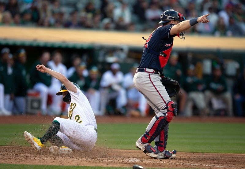 May 29, 2023; Oakland, California, USA; Oakland Athletics pinch runner Nick Allen (2) scores on an infield single by Shea Langeliers as Atlanta Braves catcher Sean Murphy (12) signals to make a relay to first during the eighth inning at Oakland-Alameda County Coliseum. Mandatory Credit: D. Ross Cameron-USA TODAY Sports