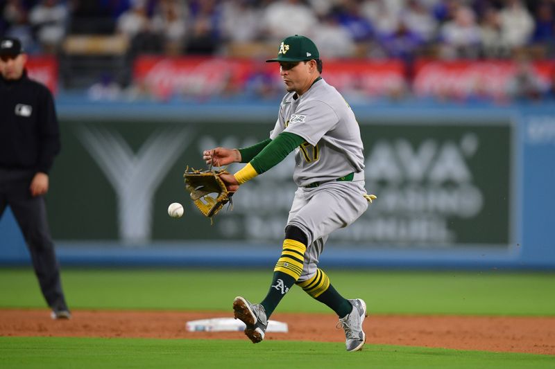 May 13, 2025; Los Angeles, California, USA; Athletics second baseman Luis Urias (17) fields the ground ball of Los Angeles Dodgers second baseman Miguel Rojas (72) during the fourth inning at Dodger Stadium. Mandatory Credit: Gary A. Vasquez-Imagn Images