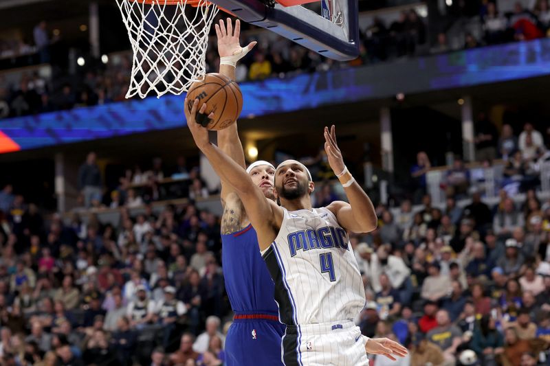 DENVER, COLORADO - JANUARY 05: Jalen Suggs #4 of the Orlando Magic goes to the basket against Aaron Gordon #50 of the Denver Nuggets in the first quarter at Ball Arena on January 05, 2024 in Denver, Colorado.  NOTE TO USER: User expressly acknowledges and agrees that, by downloading and or using this photograph, User is consenting to the terms and conditions of the Getty Images License Agreement.  (Photo by Matthew Stockman/Getty Images)