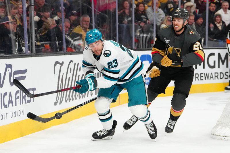 Nov 29, 2025; Las Vegas, Nevada, USA; San Jose Sharks center Barclay Goodrow (23) chips the puck ahead of Vegas Golden Knights defenseman Shea Theodore (27) during the second period at T-Mobile Arena. Mandatory Credit: Stephen R. Sylvanie-Imagn Images