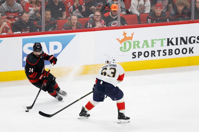 May 28, 2025; Raleigh, North Carolina, USA; Carolina Hurricanes forward Seth Jarvis (24) skates with the puck as Florida Panthers forward Brad Marchand (63) defends during the second period in game five of the Eastern Conference Final of the 2025 Stanley Cup Playoffs at Lenovo Center. Mandatory Credit: Geoff Burke-Imagn Images