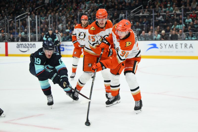 Oct 9, 2025; Seattle, Washington, USA; Anaheim Ducks defenseman Pavel Mintyukov (98) passes the puck while defended by Seattle Kraken left wing Jared McCann (19) during the second period at Climate Pledge Arena. Mandatory Credit: Steven Bisig-Imagn Images