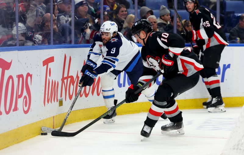 Dec 5, 2024; Buffalo, New York, USA;  Winnipeg Jets left wing Alex Iafallo (9) and Buffalo Sabres defenseman Henri Jokiharju (10) go after a loose puck along the boards during the third period at KeyBank Center. Mandatory Credit: Timothy T. Ludwig-Imagn Images