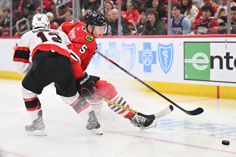 Mar 6, 2023; Chicago, Illinois, USA;  Chicago Blackhawks defenseman Connor Murphy (5) and Ottawa Senators forward Alex DeBrincat (12) battle for control of the puck in the first period at United Center. Mandatory Credit: Jamie Sabau-USA TODAY Sports