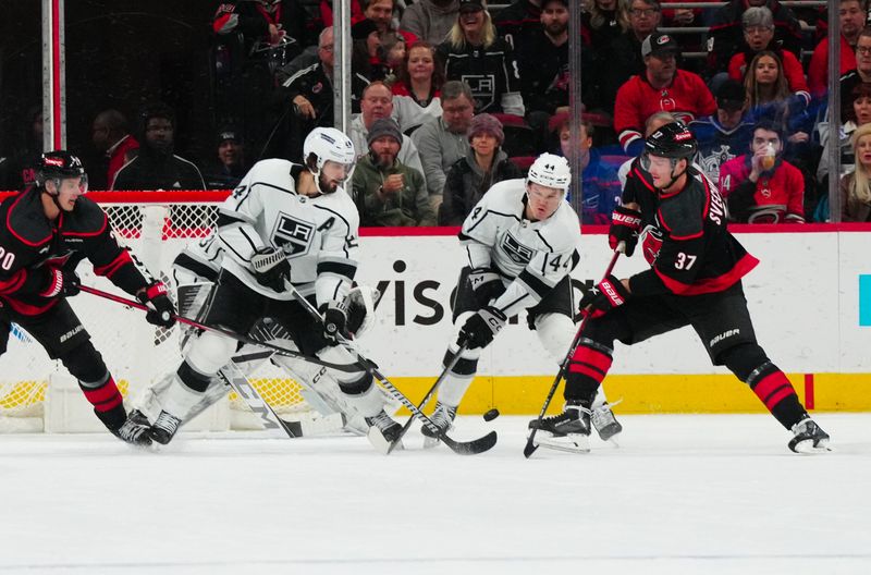 Jan 15, 2024; Raleigh, North Carolina, USA; Los Angeles Kings center Phillip Danault (24) defenseman Mikey Anderson (44) and Carolina Hurricanes right wing Andrei Svechnikov (37) watch the puck during the second period at PNC Arena. Mandatory Credit: James Guillory-USA TODAY Sports