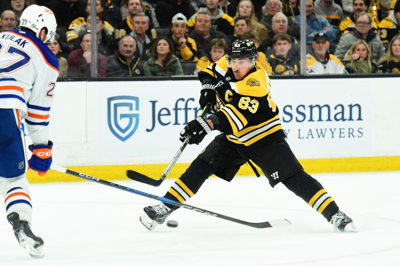 Jan 7, 2025; Boston, Massachusetts, USA;  Boston Bruins left wing Brad Marchand (63) shoots the puck while Edmonton Oilers defenseman Brett Kulak (27) defends during the third period at TD Garden. Mandatory Credit: Bob DeChiara-Imagn Images