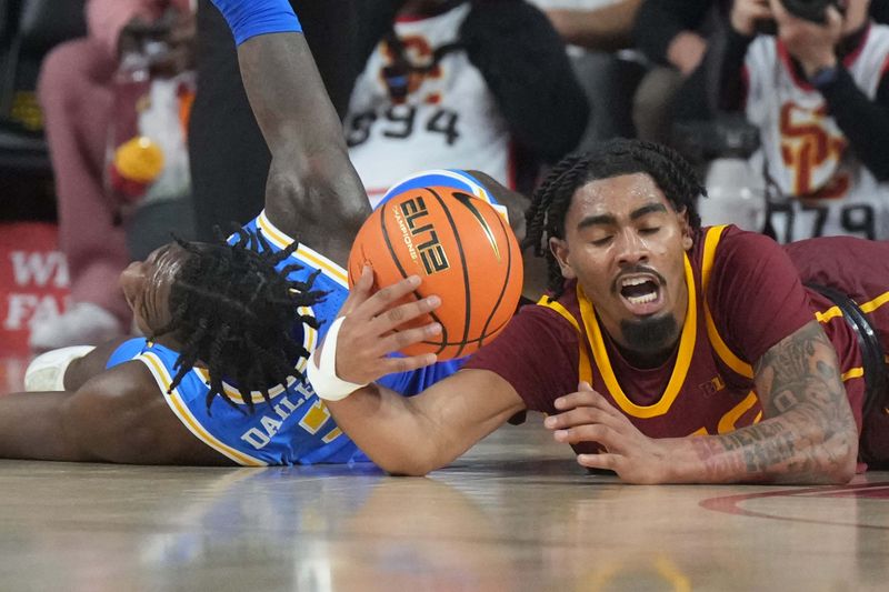 Jan 27, 2025; Los Angeles, California, USA; Southern California Trojans forward Saint Thomas (0) and UCLA Bruins guard Eric Dailey Jr. (3) reach for the ball in the second half at the Galen Center. Mandatory Credit: Kirby Lee-Imagn Images