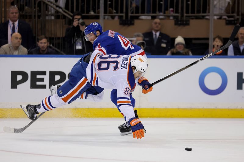 Oct 14, 2025; New York, New York, USA; Edmonton Oilers right wing David Tomasek (86) fights for the puck against New York Rangers defenseman Vladislav Gavrikov (44) during the second period at Madison Square Garden. Mandatory Credit: Brad Penner-Imagn Images