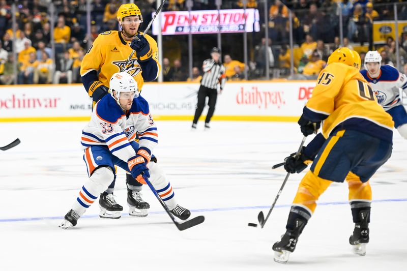 Oct 17, 2024; Nashville, Tennessee, USA;  Edmonton Oilers left wing Viktor Arvidsson (33) defends as Nashville Predators defenseman Alexandre Carrier (45) passes the puck during the second period at Bridgestone Arena. Mandatory Credit: Steve Roberts-Imagn Images