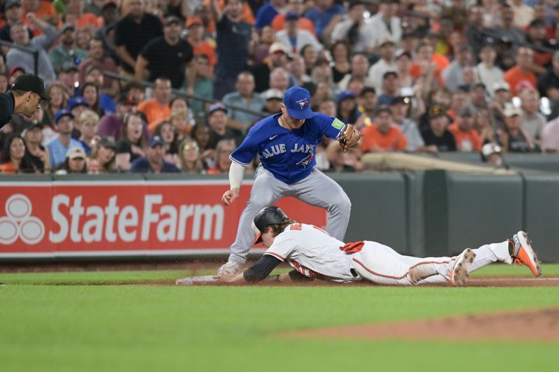 Aug 23, 2023; Baltimore, Maryland, USA;  Baltimore Orioles third baseman Gunnar Henderson (2) slides in third base before Toronto Blue Jays third baseman Matt Chapman (26) can apply a tag during the third inning at Oriole Park at Camden Yards. Mandatory Credit: Tommy Gilligan-USA TODAY Sports