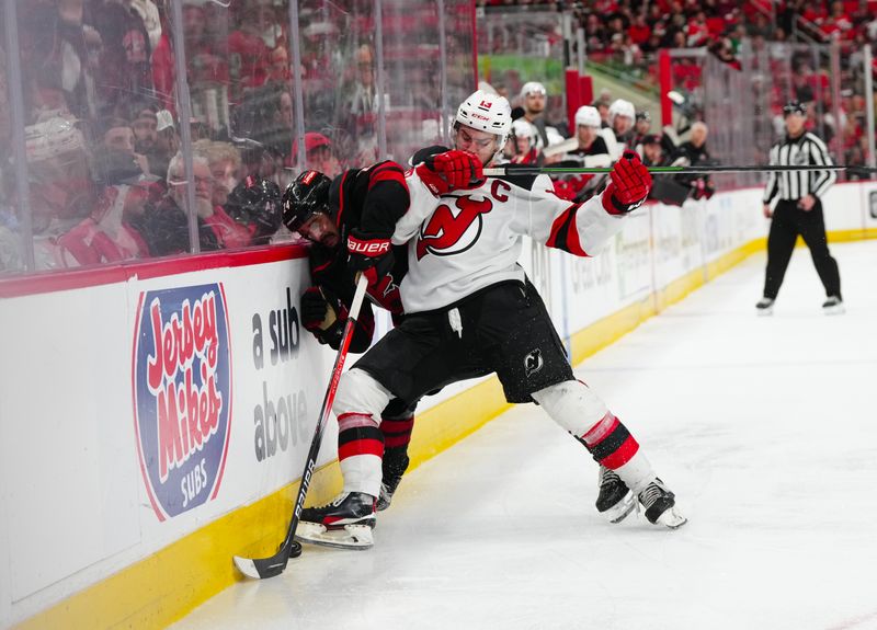 Apr 29, 2025; Raleigh, North Carolina, USA; New Jersey Devils center Nico Hischier (13) checks Carolina Hurricanes center Seth Jarvis (24) during the second overtime in game five of the first round of the 2025 Stanley Cup Playoffs at Lenovo Center. Mandatory Credit: James Guillory-Imagn Images