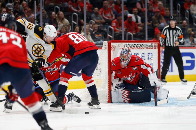 Oct 5, 2024; Washington, District of Columbia, USA; Washington Capitals goaltender Charlie Lindgren (79) allows the puck as Boston Bruins left wing Max Jones (49) and Capitals left wing Pierre-Luc Dubois (80) battle in the second period at Capital One Arena. Mandatory Credit: Geoff Burke-Imagn Images