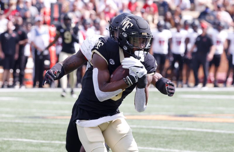 Oct 2, 2021; Winston-Salem, North Carolina, USA;  Wake Forest Demon Deacons wide receiver Jaquarii Roberson (5) catches a first down pass in front of Louisville Cardinals defensive back Qwynnterrio Cole (12) nduring the first quarter at Truist Field. Mandatory Credit: Reinhold Matay-USA TODAY Sports