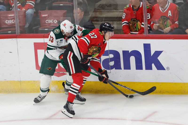 Feb 7, 2024; Chicago, Illinois, USA; Minnesota Wild defenseman Alex Goligoski (33) battles for the puck with Chicago Blackhawks left wing Lukas Reichel (27) during the first period at United Center. Mandatory Credit: Kamil Krzaczynski-USA TODAY Sports