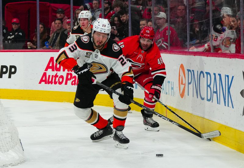 Jan 11, 2024; Raleigh, North Carolina, USA; Anaheim Ducks center Mason McTavish (23) skates with the puck past Carolina Hurricanes left wing Jordan Martinook (48) during the first period at PNC Arena. Mandatory Credit: James Guillory-USA TODAY Sports