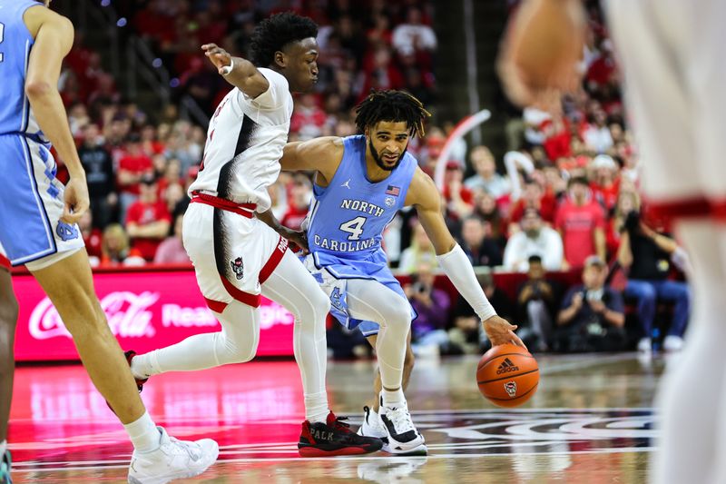 Feb 19, 2023; Raleigh, North Carolina, USA; North Carolina Tar Heels guard R.J. Davis (4) dribbles against North Carolina State Wolfpack guard Jarkel Joiner (1) during the second half of the game at PNC Arena. Mandatory Credit: Jaylynn Nash-USA TODAY Sports