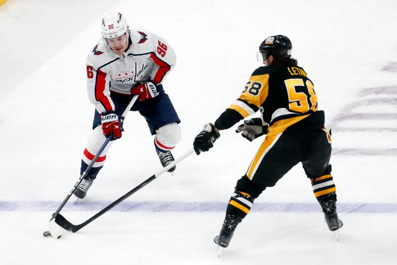 Jan 2, 2024; Pittsburgh, Pennsylvania, USA;  Washington Capitals right wing Nicolas Aube-Kubel (96) skates up ice with the puck against Pittsburgh Penguins defenseman Kris Letang (58) during the third period at PPG Paints Arena. Mandatory Credit: Charles LeClaire-USA TODAY Sports