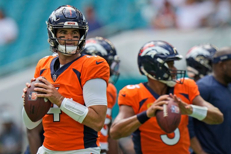 Denver Broncos quarterbacks Jarrett Stidham, left, and Russell Wilson warm up before the start of an NFL football game against the Miami Dolphins, Sunday, Sept. 24, 2023, in Miami Gardens, Fla. (AP Photo/Wilfredo Lee)