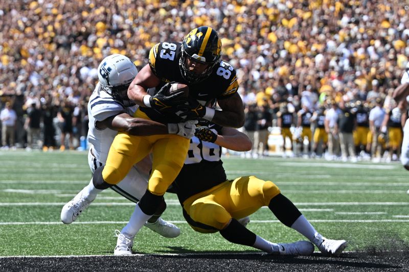 Sep 2, 2023; Iowa City, Iowa, USA; Iowa Hawkeyes tight end Erick All (83) scores on a touchdown pass as Utah State Aggies safety Anthony Switzer (1) attempts to make the tackle as Iowa tight end Steven Stilianos (86) blocks during the first quarter against the Utah State Aggies at Kinnick Stadium. Mandatory Credit: Jeffrey Becker-USA TODAY Sports