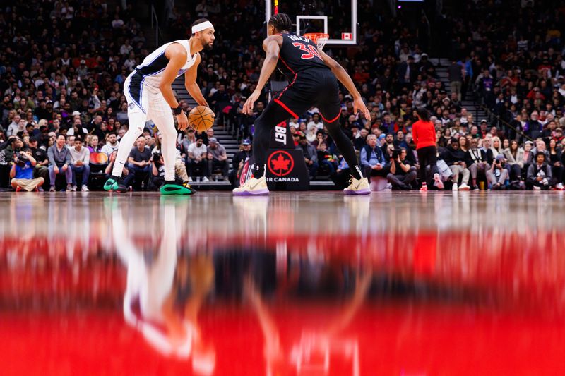 TORONTO, CANADA - JANUARY 3: Jalen Suggs #4 of the Orlando Magic dribbles the ball against Ochai Agbaji #30 of the Toronto Raptors during first half of their NBA game at Scotiabank Arena on January 3, 2025 in Toronto, Canada. NOTE TO USER: User expressly acknowledges and agrees that, by downloading and or using this photograph, User is consenting to the terms and conditions of the Getty Images License Agreement. (Photo by Cole Burston/Getty Images)