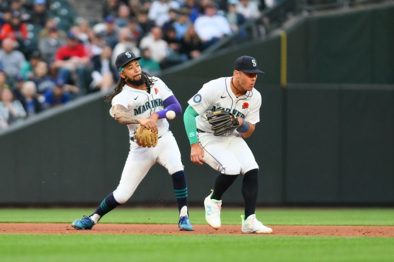 May 27, 2024; Seattle, Washington, USA; Seattle Mariners shortstop J.P. Crawford (3) throws the ball past third baseman Dylan Moore (25) for a force out against the Houston Astros during the sixth inning at T-Mobile Park. Mandatory Credit: Steven Bisig-USA TODAY Sports