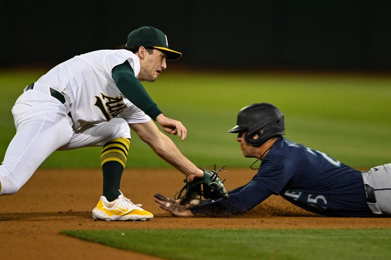 Sep 4, 2024; Oakland, California, USA; Seattle Mariners second baseman Dylan Moore (right) steals second base against Oakland Athletics shortstop Jacob Wilson (left) in the fourth inning at Oakland-Alameda County Coliseum. Mandatory Credit: Eakin Howard-Imagn Images