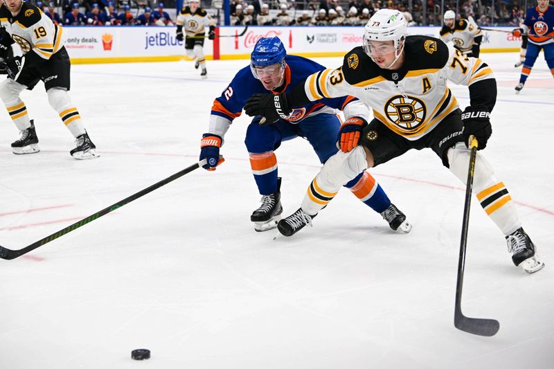 Nov 27, 2024; Elmont, New York, USA;  Boston Bruins defenseman Charlie McAvoy (73) defends against New York Islanders center Kyle MacLean (32) during the second period at UBS Arena. Mandatory Credit: Dennis Schneidler-Imagn Images