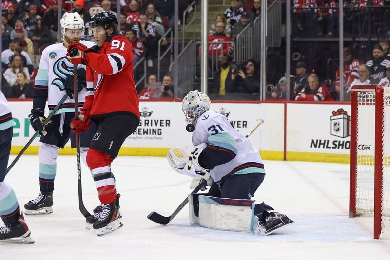 Dec 6, 2024; Newark, New Jersey, USA; Seattle Kraken goaltender Philipp Grubauer (31) makes a save through a screen by New Jersey Devils center Dawson Mercer (91) during the second period at Prudential Center. Mandatory Credit: Ed Mulholland-Imagn Images