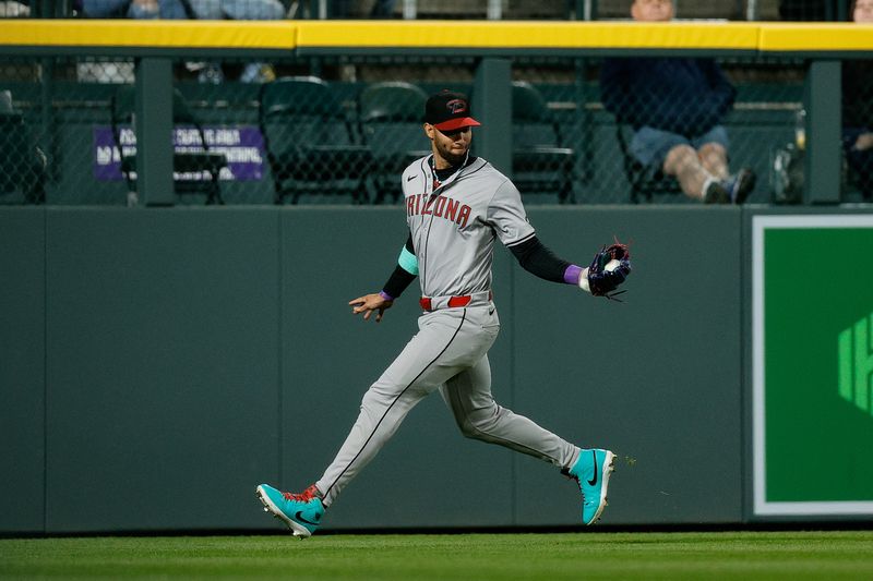 Apr 8, 2024; Denver, Colorado, USA; Arizona Diamondbacks left fielder Lourdes Gurriel Jr. (12) fields the ball in the fourth inning against the Colorado Rockies at Coors Field. Mandatory Credit: Isaiah J. Downing-USA TODAY Sports