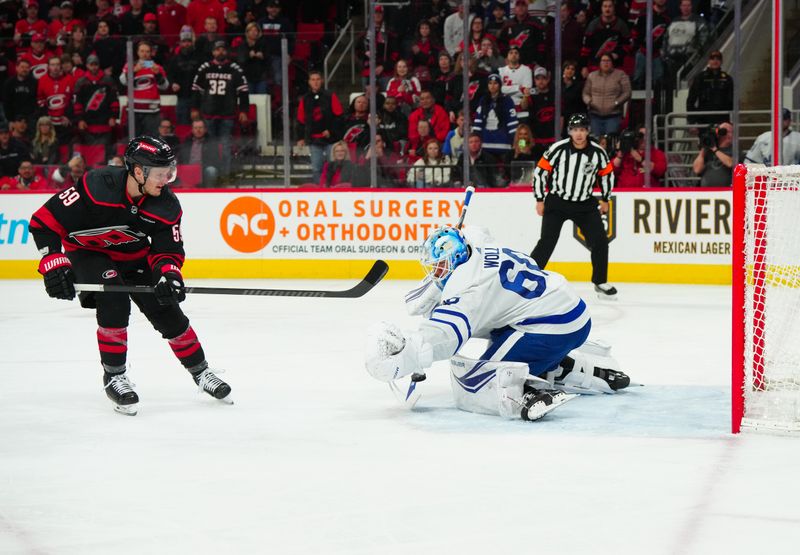 Mar 24, 2024; Raleigh, North Carolina, USA;  Toronto Maple Leafs goaltender Joseph Woll (60) stops the penalty shot by Carolina Hurricanes left wing Jake Guentzel (59) during the first period at PNC Arena. Mandatory Credit: James Guillory-USA TODAY Sports