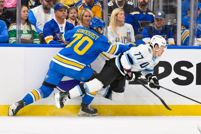 Oct 23, 2025; St. Louis, Missouri, USA; St. Louis Blues center Oskar Sundqvist (70) checks Utah Mammoth right wing JJ Peterka (77) during the first period at Enterprise Center. Mandatory Credit: Jeff Curry-Imagn Images