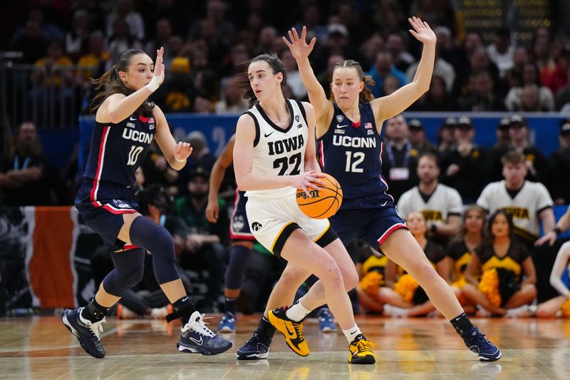 Apr 5, 2024; Cleveland, OH, USA; Iowa Hawkeyes guard Caitlin Clark (22) controls the ball against Connecticut Huskies guard Nika Muhl (10) and guard Ashlynn Shade (12) in the fourth quarter in the semifinals of the Final Four of the womens 2024 NCAA Tournament at Rocket Mortgage FieldHouse. Mandatory Credit: Kirby Lee-USA TODAY Sports