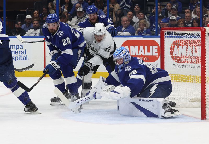 Jan 30, 2025; Tampa, Florida, USA;  Los Angeles Kings left wing Trevor Moore (12) and Tampa Bay Lightning left wing Nick Paul (20) skate for the puck as Tampa Bay Lightning goaltender Andrei Vasilevskiy (88) defends during the second period at Amalie Arena. Mandatory Credit: Kim Klement Neitzel-Imagn Images