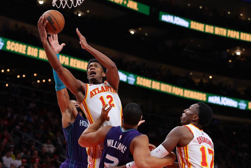 ATLANTA, GEORGIA - OCTOBER 25:  De'Andre Hunter #12 of the Atlanta Hawks scores as he drives against Miles Bridges #0 and Grant Williams #2 of the Charlotte Hornets during the fourth quarter at State Farm Arena on October 25, 2024 in Atlanta, Georgia.  NOTE TO USER: User expressly acknowledges and agrees that, by downloading and/or using this photograph, user is consenting to the terms and conditions of the Getty Images License Agreement.  (Photo by Kevin C. Cox/Getty Images)